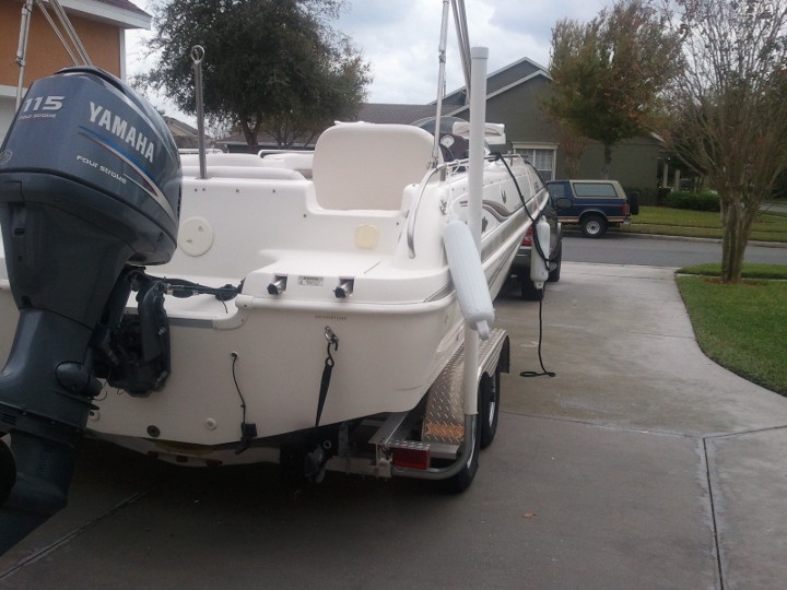 Boat on a trailer with a Yamaha outboard motor, parked in a driveway. A blue SUV is visible in the background
