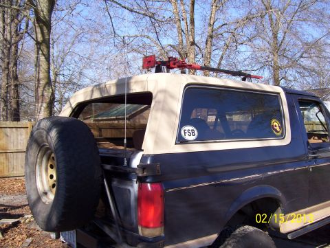 1990 Ford Bronco - Rear quarter of a two-tone Ford Bronco with spare tire, roof rack, hi-lift jack and an FSB window decal.