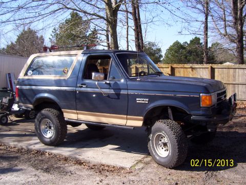 1990 Ford Bronco - This 1990 Ford Bronco features a lifted suspension and a roof rack, with visible 'Bronco' badging on the fender.