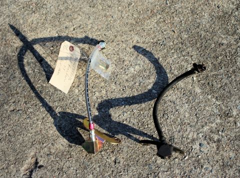 1976 Ford Ranchero - Two automotive brake hoses lie on a concrete surface, one with a handwritten tag attached.