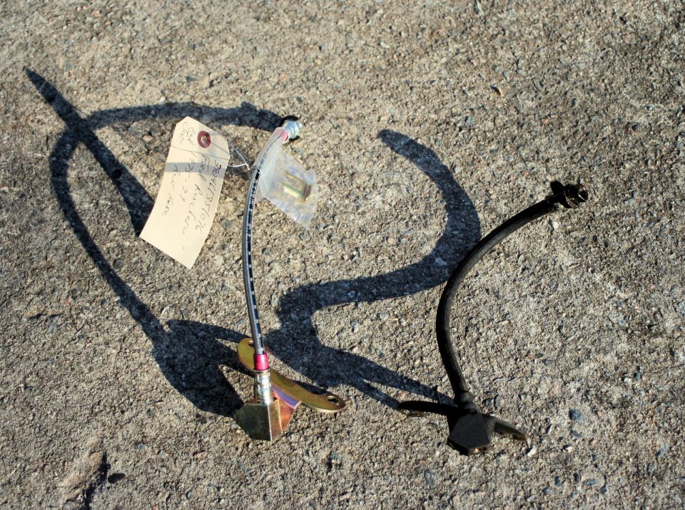 Two brake hoses on the ground, one with a tag that says "4/13/10 Ranchero"