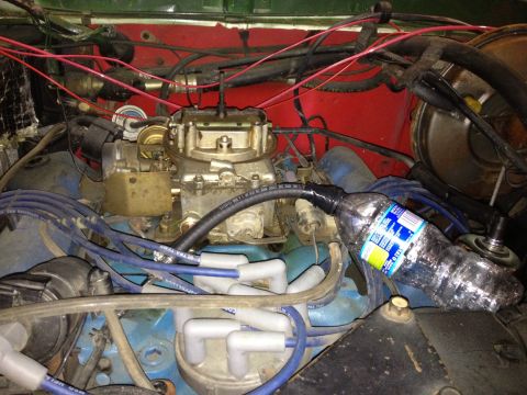 1978 Ford Bronco - The engine bay of a 1978 Ford Bronco is visible, a carburetor and a makeshift fuel line using a plastic bottle.