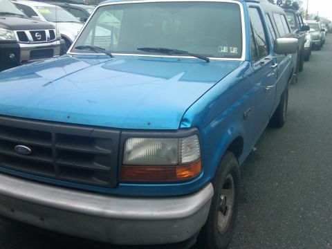 1993 Ford Bronco - A blue Ford F-Series truck is parked in a lot with other vehicles visible in the background.