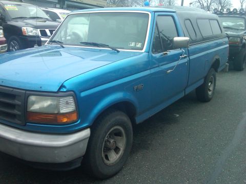 1993 Ford Bronco - This blue 1993 Ford F-150 pickup truck is seen from the front-three-quarter angle, equipped with a camper shell.