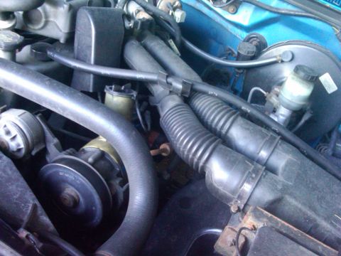 1993 Ford Bronco - The engine bay of a 1993 Ford Bronco is visible, various components and blue exterior paint.