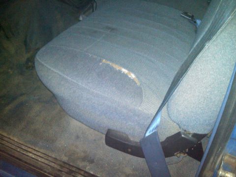 1993 Ford Bronco - Interior view of a worn seat with a torn section and visible seatbelt.