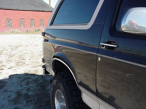 1993 Ford Bronco - This 1993 Ford Bronco shows its rear quarter panel and tire, with a red brick building behind it.