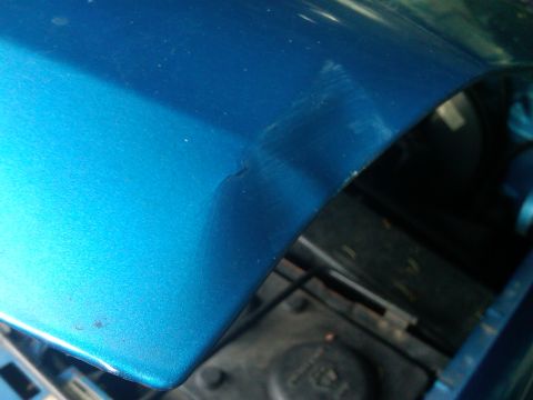 1993 Ford Bronco - Detail of a blue fender, showing paint imperfections and a slight crease.