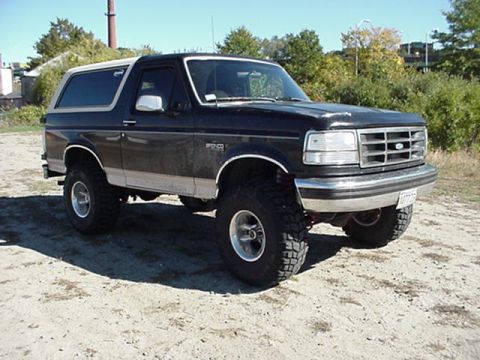 1993 Ford Bronco - This 1993 Ford Bronco is shown from a three-quarter front angle, highlighting its lifted stance and off-road modifications.