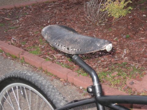 1994 Ford Bronco - A close-up view of a bicycle's worn black seat and part of its wheel.