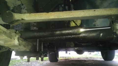 1982 Jeep Wagoneer - Underside view of vehicle steering and suspension components, showing a greasy tie rod and leaf springs.