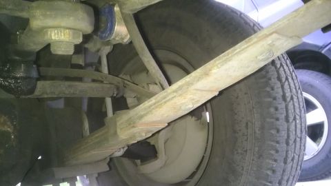 1982 Jeep Wagoneer - Underside view of a vehicle's suspension system, showing a leaf spring and tire. Another vehicle is partially visible.