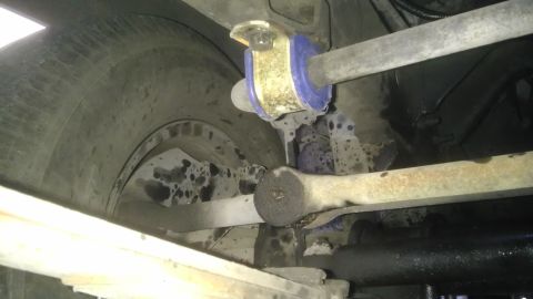 1982 Jeep Wagoneer - Undercarriage view focusing on suspension components and a tire, with visible blue polyurethane bushings.