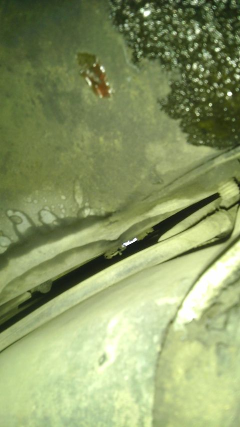 1982 Jeep Wagoneer - This image shows the underside of a vehicle, with evidence of oil leaks and a dark channel, but no clear identification of the make or mode…