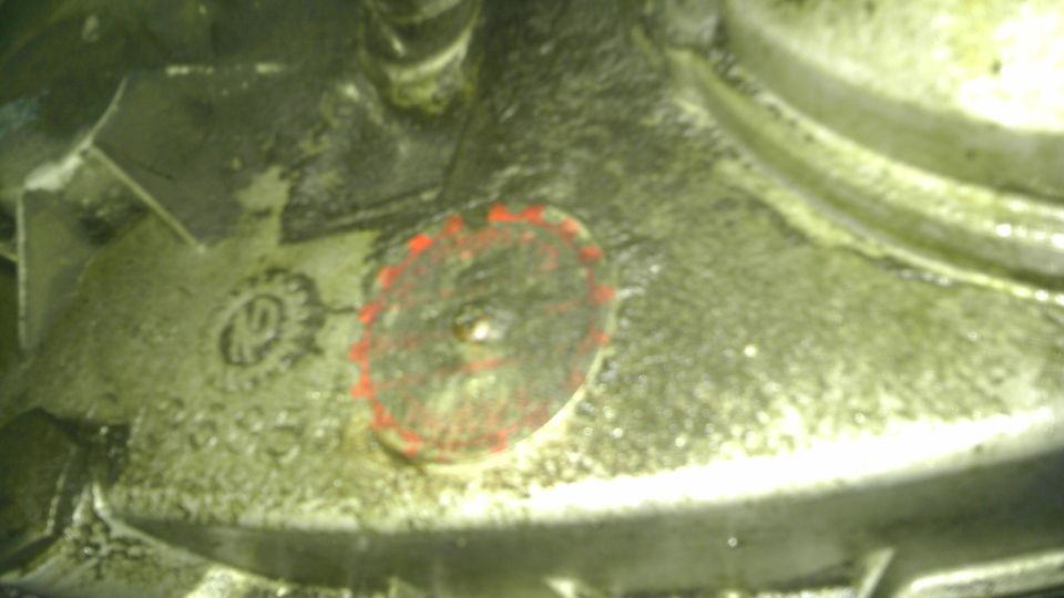 Engine part with a red-ringed bolt and stamped numbers