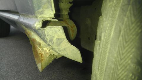1982 Jeep Wagoneer - Close-up of a rusted metal bracket and tire tread, likely from a vehicle's undercarriage.