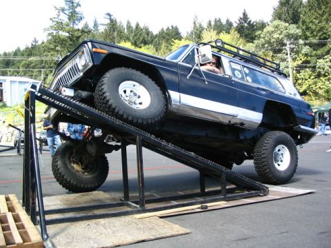 1982 Jeep Wagoneer - A modified Jeep Wagoneer is shown on a steep metal ramp, demonstrating its off-road capabilities.