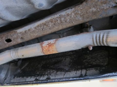 1991 Ford LTD Crown Victoria - The undercarriage of a vehicle displays significant rust on its frame and exhaust system components.