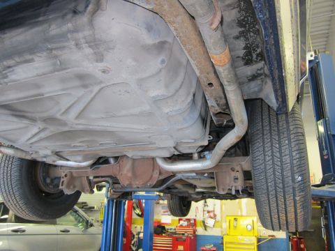 1991 Ford LTD Crown Victoria - The underside of a vehicle is shown on a lift, revealing its fuel tank and exhaust components.