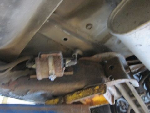 1991 Ford LTD Crown Victoria - Undercarriage view of a vehicle's fuel filter, showing rust and a white securing strap.