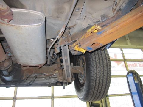 1991 Ford LTD Crown Victoria - Undercarriage view of a 1991 Ford Crown Victoria LTD, highlighting the rear suspension components and the large muffler.