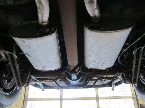 1991 Ford LTD Crown Victoria - The undercarriage of a vehicle shows its dual exhaust system, mufflers, and driveshaft.