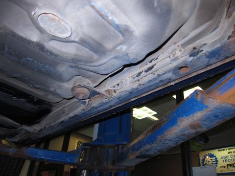 1991 Ford LTD Crown Victoria - Underside of a 1991 Ford Crown Victoria LTD, showing rust and wear on the frame and suspension parts.