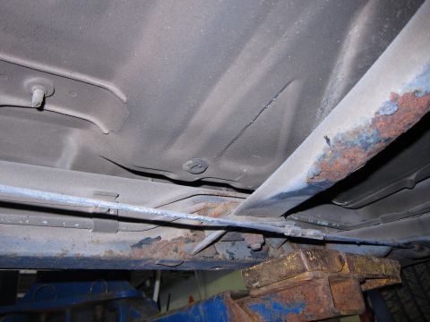 1991 Ford LTD Crown Victoria - The undercarriage of a vehicle is shown, with visible rust on the frame and support structures.