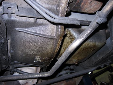 1991 Ford LTD Crown Victoria - Underside view of a vehicle's transmission and oil pan, showing components and oil residue.