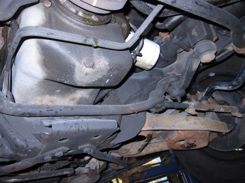 1991 Ford LTD Crown Victoria - The underside of a vehicle shows the oil pan, filter, and suspension parts, with some signs of wear and tear.