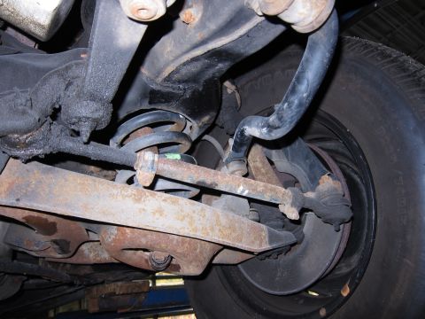 1991 Ford LTD Crown Victoria - Close-up view of the rusty suspension components and tire of an unidentified vehicle.
