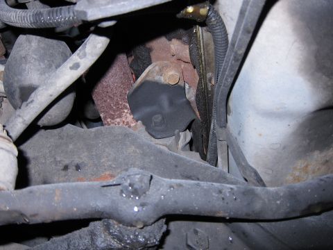 1991 Ford LTD Crown Victoria - Underside view of engine components, including a motor mount and exhaust pipe connection.