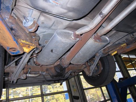 1991 Ford LTD Crown Victoria - The rear undercarriage of a 1991 Ford Crown Victoria LTD is visible, including its dual exhaust system and suspension components.