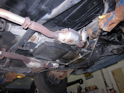 1991 Ford LTD Crown Victoria - The underside of a vehicle is visible, including the exhaust pipes, catalytic converter, and transmission pan. No specific year can be dete…