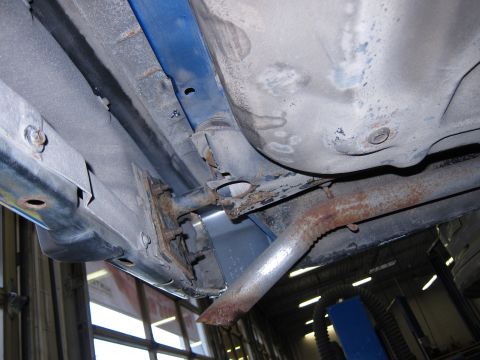1991 Ford LTD Crown Victoria - The undercarriage of a vehicle reveals significant rust on the exhaust system and structural components.