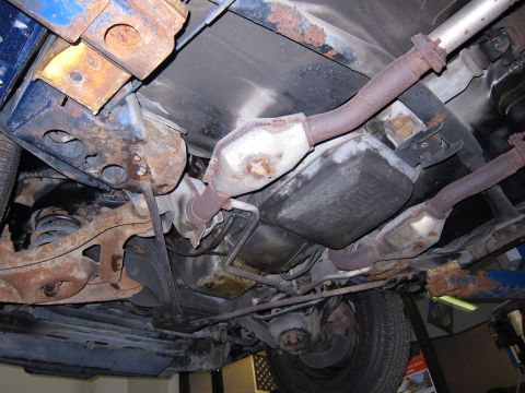 1991 Ford LTD Crown Victoria - The undercarriage of a vehicle displays significant rust on its suspension and exhaust components.