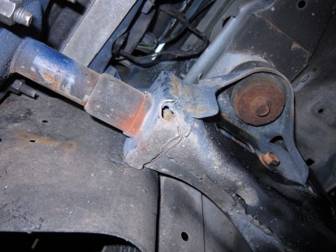 1991 Ford LTD Crown Victoria - Close-up view of rusted suspension parts and wiring harness on a vehicle's undercarriage.