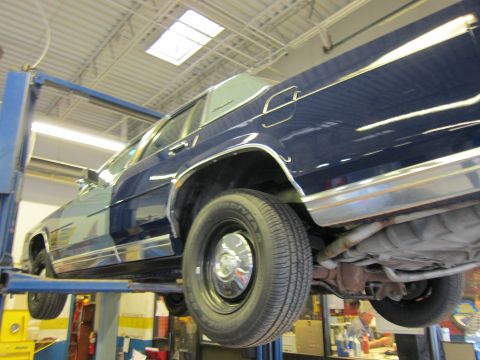 1991 Ford LTD Crown Victoria - Side view of a blue 1991 Ford Crown Victoria LTD being serviced on a car lift.