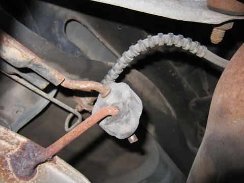1991 Ford LTD Crown Victoria - Close-up view of an exhaust hanger assembly, showing a rubber isolator connecting rusty metal components.