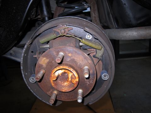 1991 Ford LTD Crown Victoria - This photo shows a rear drum brake assembly, likely from a car or truck, with visible rust on the hub and drum.