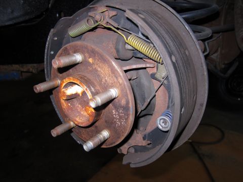 1991 Ford LTD Crown Victoria - Close-up view of a worn car brake drum and hub assembly, showing internal brake components.