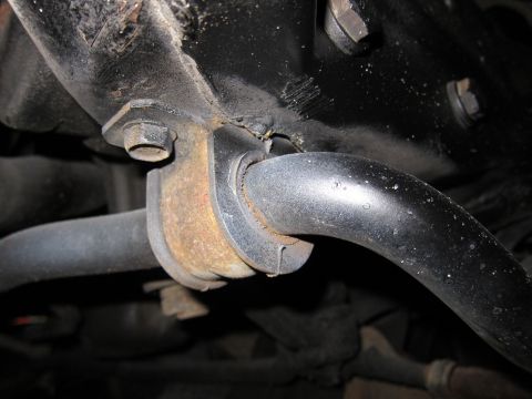 1991 Ford LTD Crown Victoria - Underside view of a vehicle's sway bar and its rusty mounting hardware.