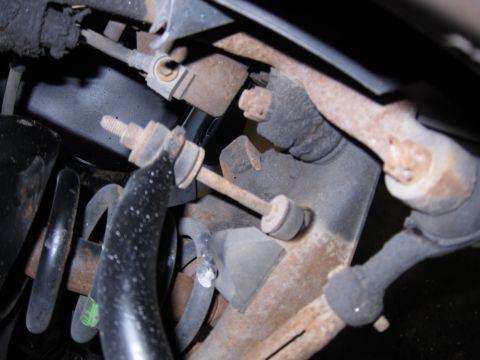 1991 Ford LTD Crown Victoria - The photo shows a close-up view of rusted suspension parts on a vehicle, including a sway bar link and coil spring.