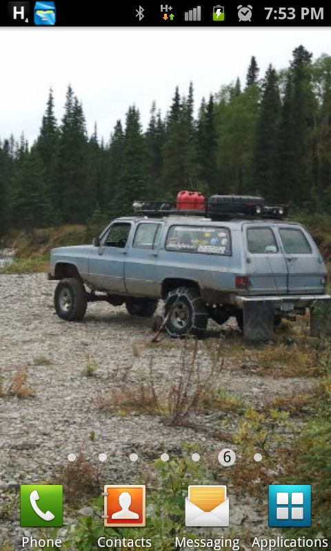 1990 Chevrolet Suburban - Modified 1990 Chevrolet Suburban parked in a rocky, wooded area with a roof rack, spare tire, and auxiliary gas can.