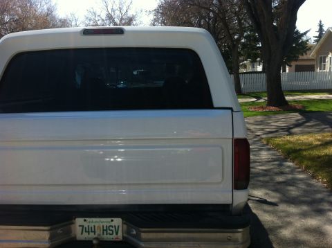 1994 Ford Bronco - This white SUV, possibly a Ford Bronco, is seen from the rear with a camper shell and a Saskatchewan license plate.