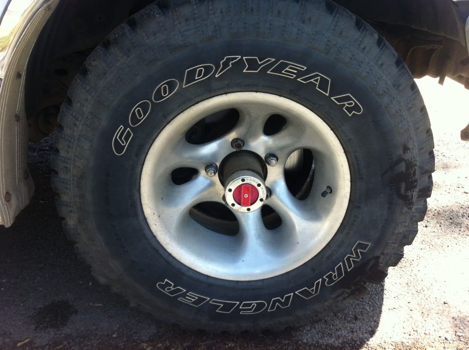 Close-up of a Goodyear Wrangler tire on a silver 5-spoke wheel with a red and silver hub