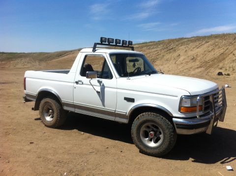 1994 Ford Bronco - This white Ford Bronco is parked in a dry, dusty area under a clear blue sky.