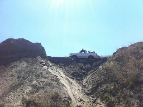 1994 Ford Bronco - Pickup truck parked on the edge of a steep dirt hill with a dirt bike in the truck bed.