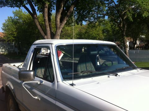 1994 Ford Bronco - This white Ford Bronco is viewed from the front passenger side, revealing its side mirror and door.
