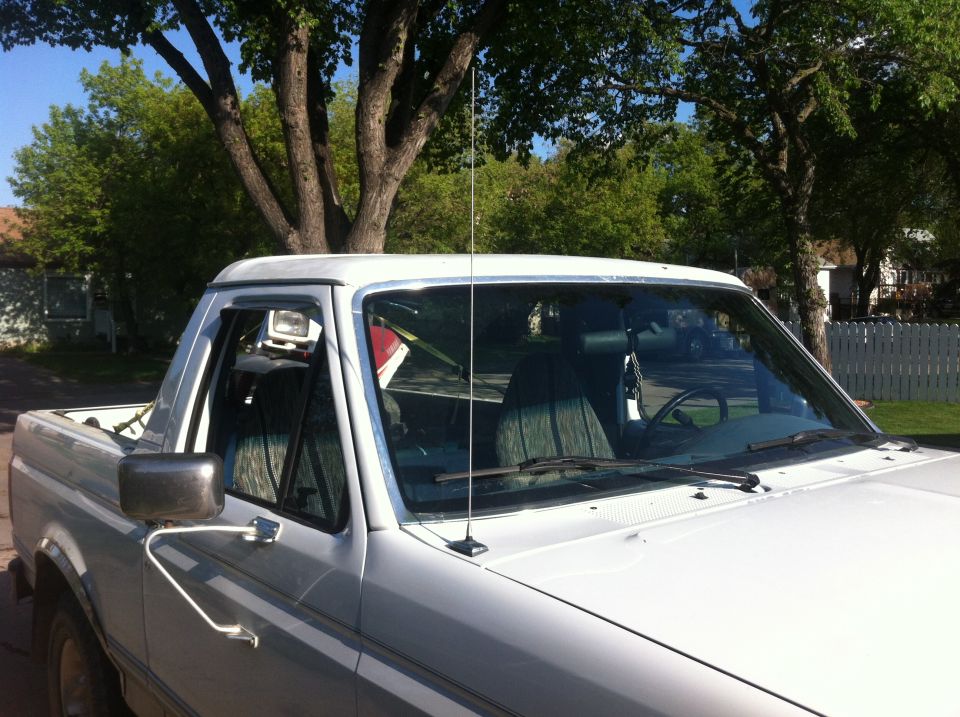 White Ford Bronco from the front passenger side, showing the side mirror, door, and part of the windshield and roof